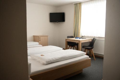 a room with two beds and a desk and a television at Frühstückspension Auer - Haus Kargl in Schladming