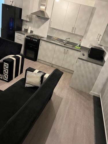 a living room with a black couch in a kitchen at Heyor’s place in Barking