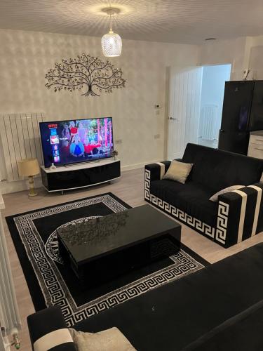 a living room with a black couch and a tv at Heyor’s place in Barking