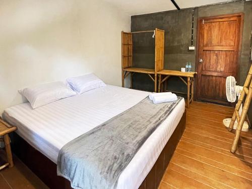 a bedroom with a bed and a wooden door at Little Hut in Ko Phayam