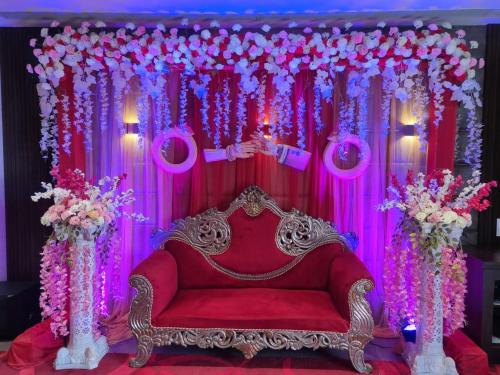 a red couch in front of a stage with flowers at The Onyx Hotel in Jamshedpur