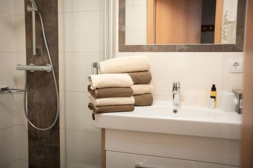 ein Bad mit einem Waschbecken, einer Dusche und Handtüchern in der Unterkunft Frühstückspension Auer - Haus Kargl in Schladming