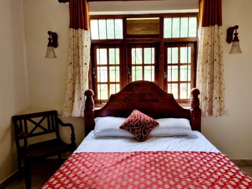 um quarto com uma cama com um cobertor vermelho e branco em JAYANDRA HOLIDAY BUNGALOW 