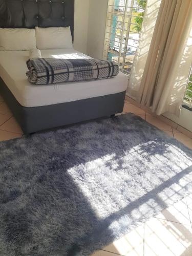 a bedroom with a bed with a rug and a window at HUNTERS NEST GUEST HOUSE BRONKHORSTSPRUIT in Erasmus