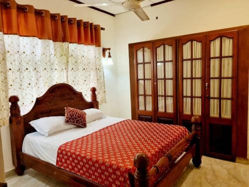 a bedroom with a wooden bed with a red blanket at JAYANDRA HOLIDAY BUNGALOW in Waga