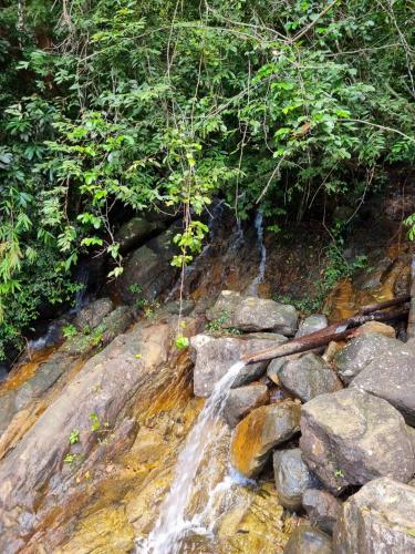 a waterfall on the side of a river with rocks at JAYANDRA HOLIDAY BUNGALOW in Waga