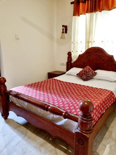 a bedroom with a wooden bed with a red blanket at JAYANDRA HOLIDAY BUNGALOW in Waga
