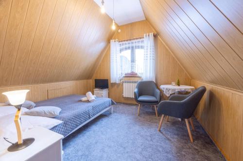 a bedroom with a bed and two chairs and a window at U Majerczyka in Zakopane