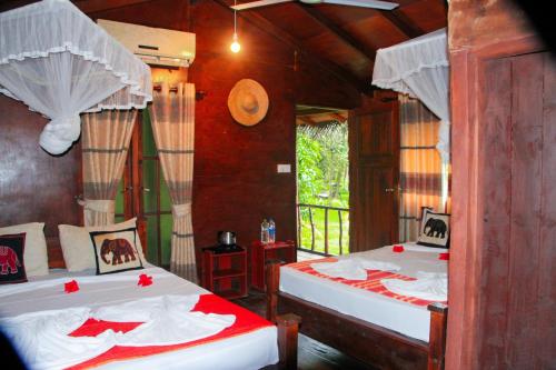 a bedroom with two beds with red and white sheets at Kolon Resort Sigiriya in Sigiriya