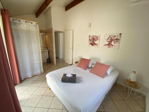 a bedroom with a white bed with two pink pillows at Villa détente vue mer st leu 6 personnes in Saint-Leu