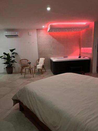 a bedroom with a bed and a bathtub with a pink light at La Suite du clocher in Noves