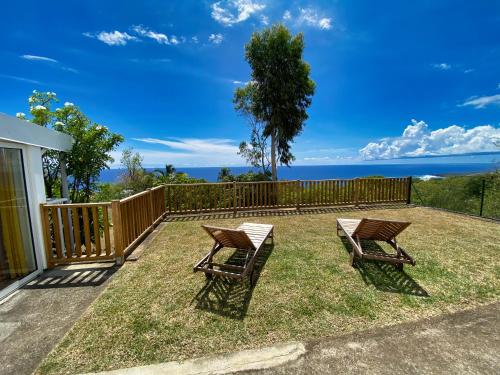 two chairs and a table on a yard with the ocean at Villa détente vue mer st leu 6 personnes in Saint-Leu