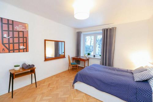 1 dormitorio con cama, escritorio y ventana en Bright and elegant apartment in the green area!, en Varsovia