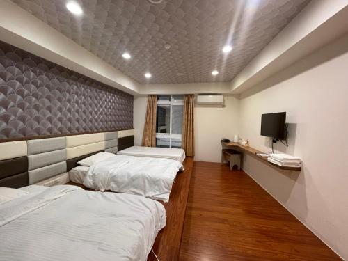 Habitación con 3 camas y TV en la pared. en Dong Yong Travel, en Dongyin/