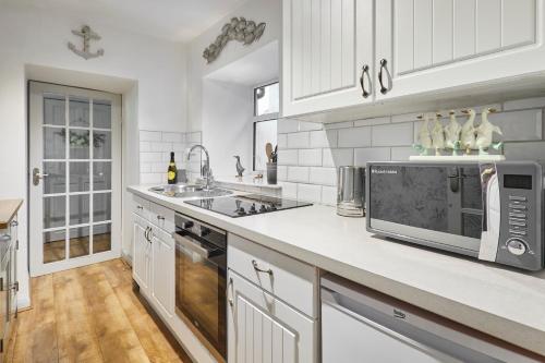 a white kitchen with a sink and a microwave at Host & Stay - Camwy Cottage in Brynsiencyn