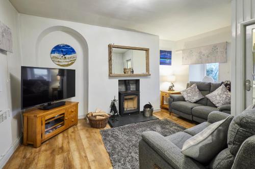 a living room with a tv and a couch and a fireplace at Host & Stay - Camwy Cottage in Brynsiencyn