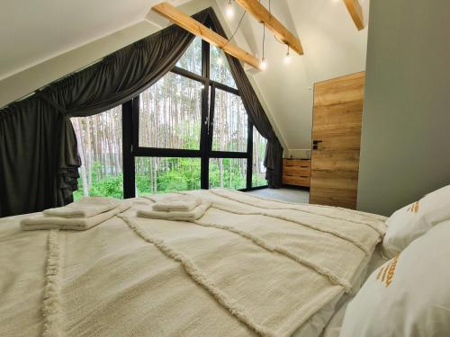 a bedroom with a large bed with a large window at LEŚNA STODOŁA in Łubiana