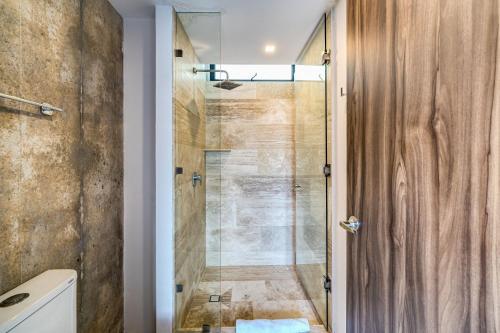 a bathroom with a shower with a glass door at Divine 1BR PH Tulum w Private Pool, Cenote, Gym in Tulum