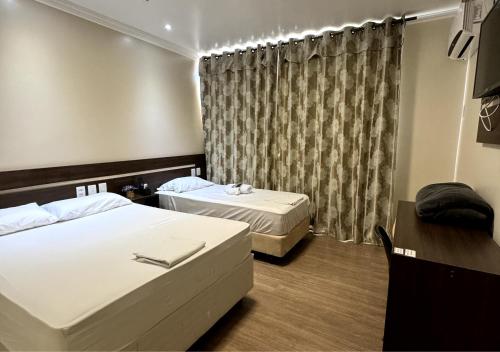a hotel room with two beds and a window at Hotel Maravilha in Caçapava do Sul