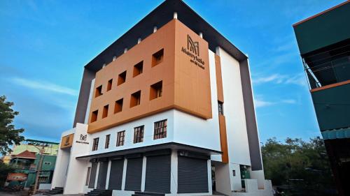 a building with an orange and white at Hotel Merrytale in Kurinjippādi