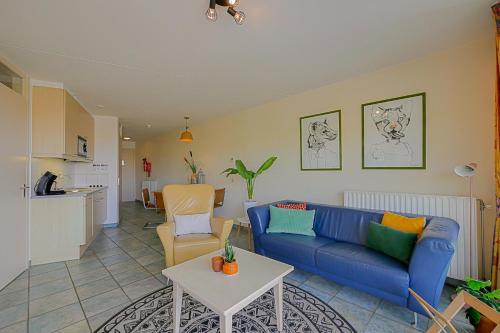 a living room with a blue couch and a table at Appartement Wijde Blick 207 - Callantsoog aan Zee in Callantsoog