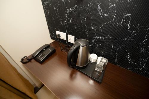 a coffee maker and a phone on a wooden desk at Hotel Merrytale in Kurinjippādi