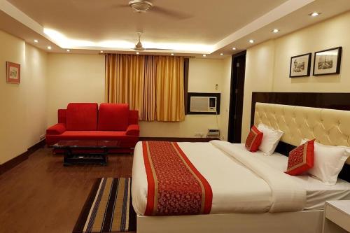a hotel room with a bed and a red chair at Greenleaf Apartment and Suites, Kalkaji in New Delhi