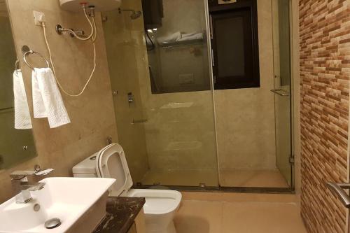 a bathroom with a shower and a toilet and a sink at Greenleaf Apartment and Suites, Kalkaji in New Delhi