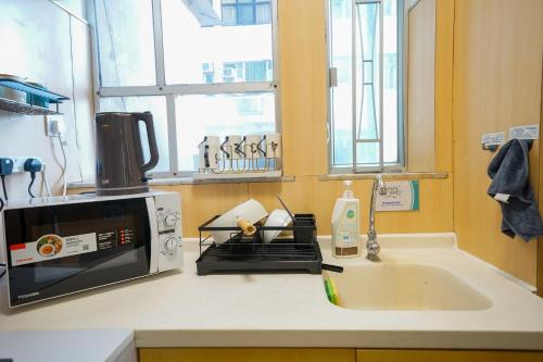 encimera de cocina con microondas y fregadero en Student Accommodation - 276 Gloucester Road, en Hong Kong