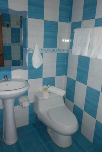 a blue and white bathroom with a toilet and a sink at Hotel Venecia in Huánuco