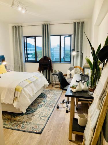 a bedroom with a bed and a living room with windows at 504 on Wilderness in Cape Town