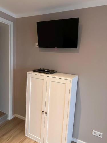 biała szafka z telewizorem z płaskim ekranem na ścianie w obiekcie Appartement 2 Birkenhof w mieście Drolshagen