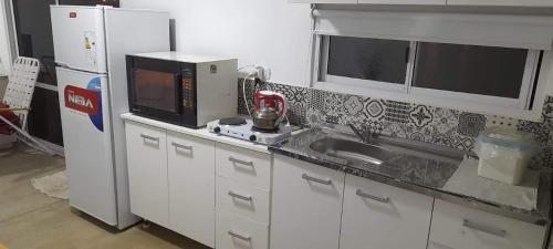 a kitchen with a sink and a microwave at Hostal del Sol Rosario in Rosario