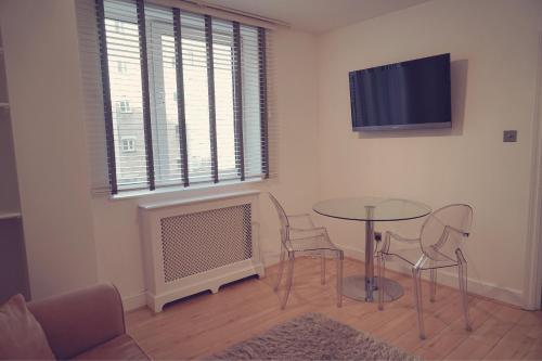 a living room with a table and chairs and a tv at One Bedroom in Chelsea in London