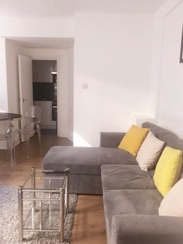 sala de estar con sofá gris y almohadas amarillas en One Bedroom in Chelsea en Londres