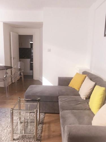 a living room with a gray couch and yellow pillows at One Bedroom in Chelsea in London