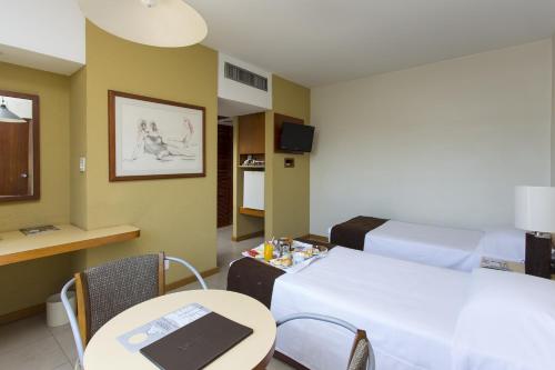 a room with a bed and a table with a laptop on it at Black Stream Hotel in Ribeirão Preto