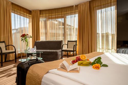 Cette chambre d'hôtel comprend un lit avec un livre et des fruits. dans l'établissement Europe Hotel, à Sofia