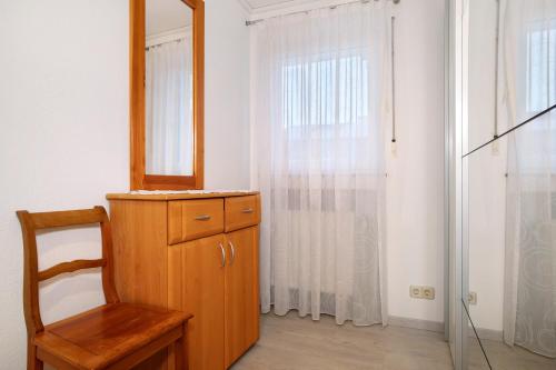 um espelho e uma cómoda de madeira e uma cadeira num quarto em Haus Loser em Wasserburg