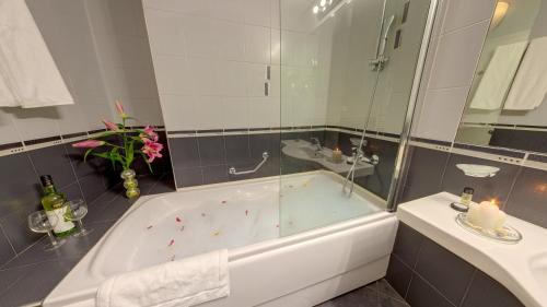 a bathroom with a tub and a sink with a candle at Europe Hotel in Sofia