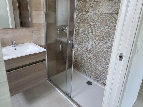 une douche avec une porte vitrée à côté d'un lavabo dans l'établissement Villa Bruna, 8 pers, piscine, 15 minutes plage en voiture, à Capo
