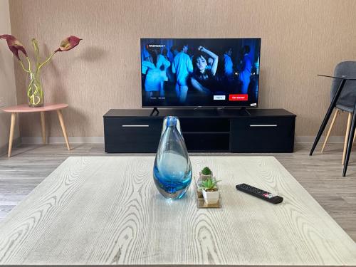 a vase sitting on a table in front of a tv at Horizon House, Stunning 2-Bedroom Flat 1, Parking, Netflix, Oxford in Oxford