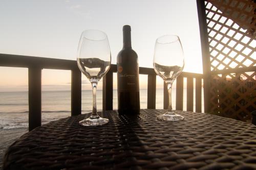 two wine glasses sitting on a table with a bottle of wine at Sunset Views - Acogedor con vista al mar in La Libertad