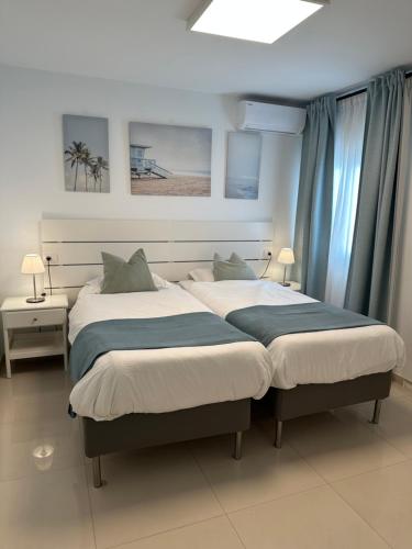 two beds in a bedroom with blue curtains at Apartamento Olivin in Puerto del Carmen