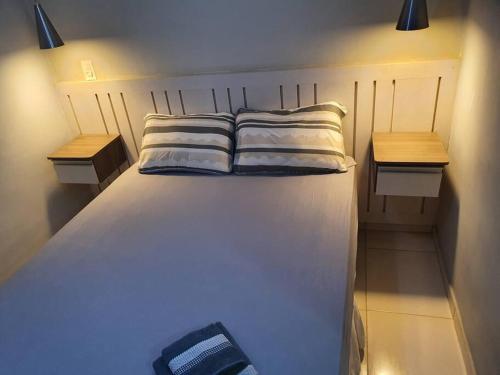 duże białe łóżko z 2 szafkami nocnymi i 2 poduszkami w obiekcie Casa em condomínio fechado w mieście Uberaba