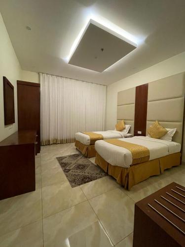 a hotel room with two beds and a television at فندق راية الشلال in Hafr Al-Batin
