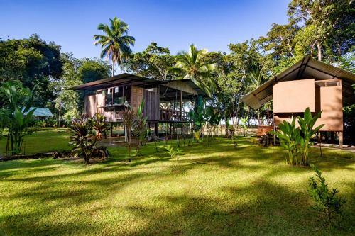 a house in the middle of a grass yard at Playa Ganadito Ecolodge in Drake