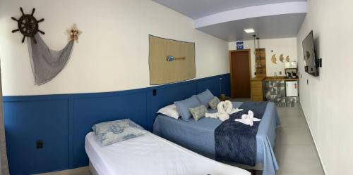 a bedroom with a blue bed and a small couch at Pousada Águas da Grota in Penha