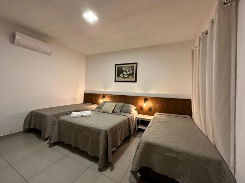 a hotel room with two beds and a table at Hotel Morro De Santo Agostinho in Serra Negra