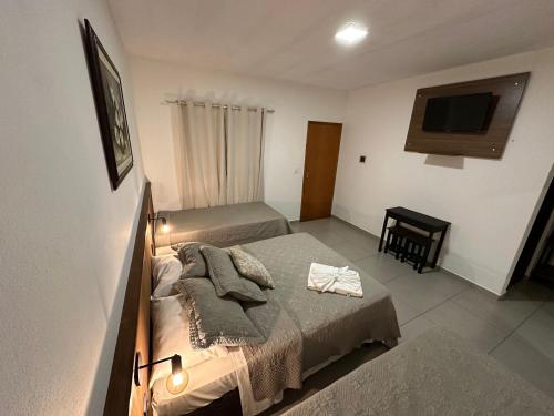 a bedroom with two beds and a television in it at Hotel Morro De Santo Agostinho in Serra Negra